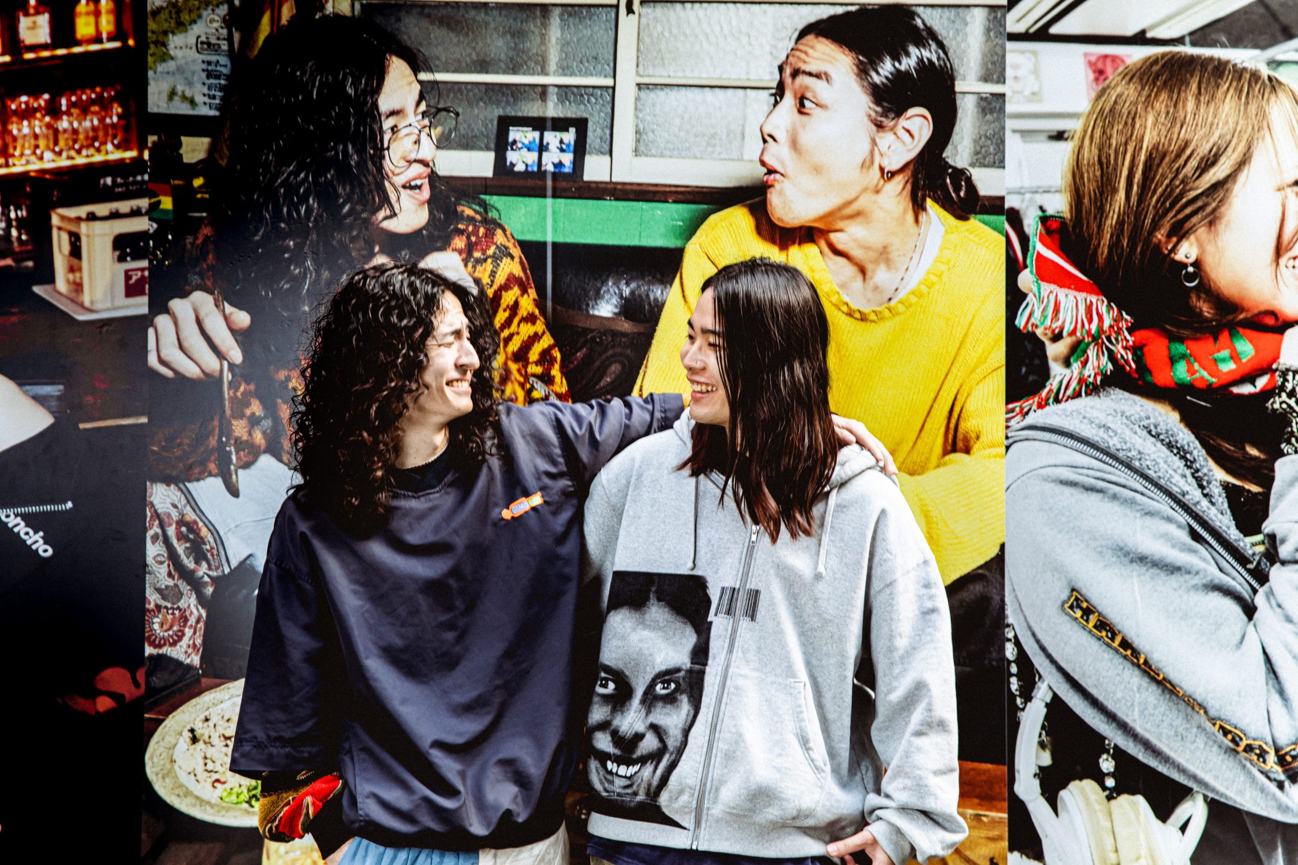 渋谷・道玄坂に掲出されたNewMatch超大型OOH広告(縦1.7m×横10m)の前に立つモデル2人。